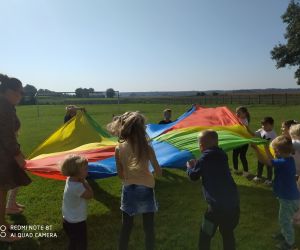 dzieci wraz z nauczycielką energicznie podnoszą i opuszczają chustę animacyjną