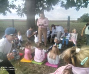 dzieci siedzą na trawce, konsumują ziemniaki, rozmawiają