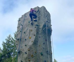 Dziewczynka znajduje się na szczycie ściany wspinaczkowej