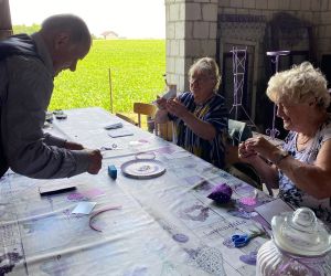 Seniorzy siedzą przy stole, są zajęci wykonywaniem pracy plastycznej