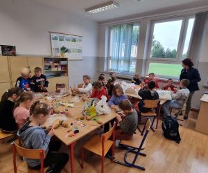  Dzieci przy stolikach wykonują ludki z ziemniaków
