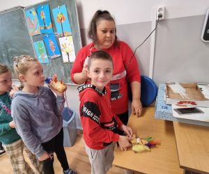  Uczniowie przy pomocy Pani przyklejają ozdoby klejem na gorąco
