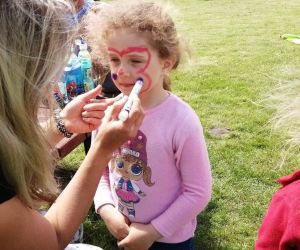 Nauczycielka maluje motyla na twarzy dziewczynki