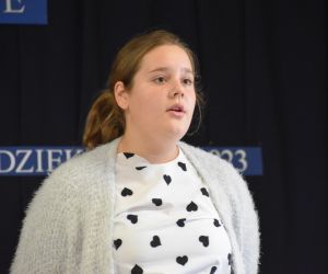 Zdjęcie przedstawia recytującą dziewczynkę.