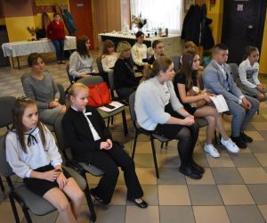 Zdjęcie przedstawia dzieci i młodzież, którzy siedzą na krzesłach.