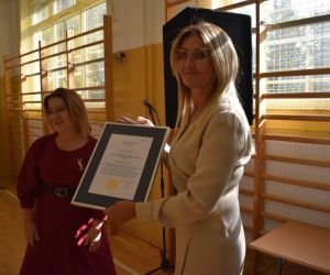 Dyrektor szkoły prezentuje dyplom pamiątkowy. Obok Pani wizytator