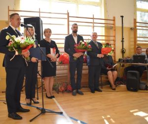 Pan Wójt wygłasza przemówienie. Obok zaproszeni goście z kwiatami w rękach