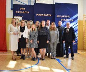 Nauczyciele szkoły na tle tablicy dekoracyjnej