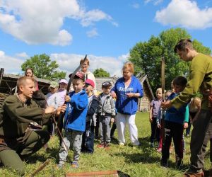 Mężczyźni w strojach wojowników gockich uczą dzieci strzelać z łuku