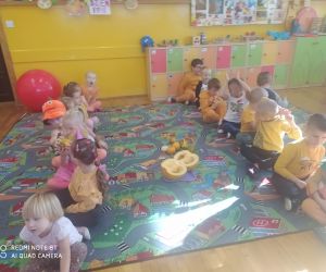 dzieci podają sobie dynię w pozycji siedzącej
