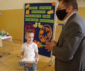 Mężczyzna i chłopiec w kolorowej koszulce. Chłopiec trzyma w rękach dyplom i nagrodę