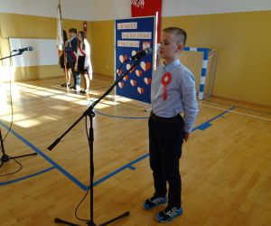 Uczeń w stroju galowym recytuje przy mikrofonie