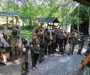 Uczniowie w mundurach polowych stojący przodem słuchają instrukcji prowadzącego