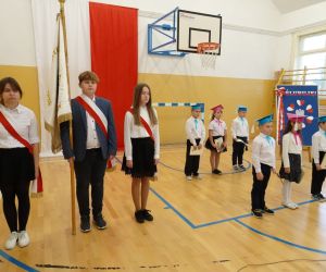 Poczet sztandarowy szkoły - chłopiec i dwie dziewczynki obok pierwszoklasistów