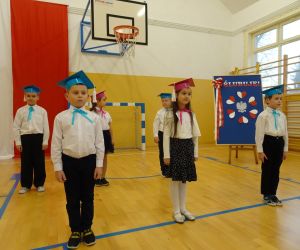 Pierwszoklasiści w strojach galowych i biretach przed uroczystością