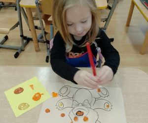 Dziewczynka maluje farbami misia na kartonie