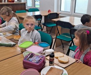 Dzieci siedzą przy stole syto zastawionym przez produkty spożywcze.