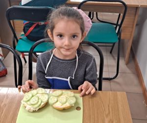 Dziewczynka siedzi przy stoliku z kanapkami.