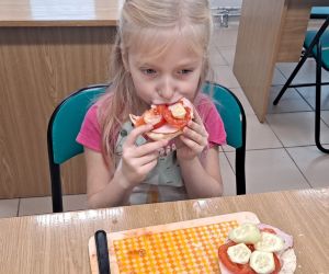 Dziewczynka konsumuje kanapkę.