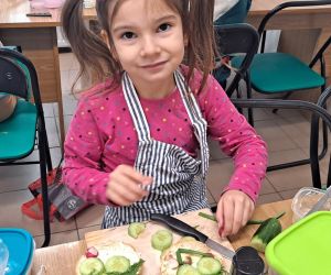 Dziewczynka w fartuszku uśmiecha się do zdjęcia.