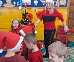 Dzieci tańczą wraz z nauczycielką w kole trzymając się za ręce.