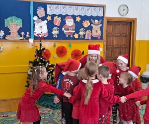 Dzieci tańczą wraz z nauczycielką w kole trzymając się za ręce.