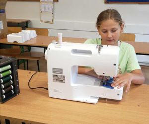 Uczennica zszywa materiał przy użyciu maszyny do szycia