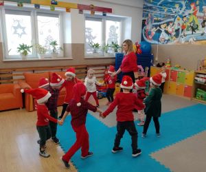 Dzieci w strojach mikołajowych podczas zabawy w kółeczku z wychowawczynią