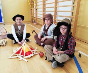 Uczniowie przebrani za pastuszków siedzą przy sztucznym ognisku