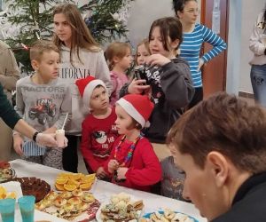 Dzieci i rodzice zgromadzeni przy stole ze słodkościami