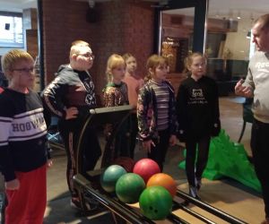  Nauczyciel instruuje dzieci jak powinny grać w kręgle