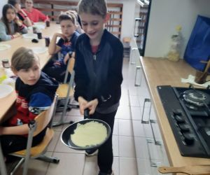 Chłopiec podrzuca naleśnik na patelni