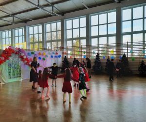 Uczniowie tańczą w kółku z nauczycielką