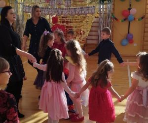 Dzieci z klas młodszych tańczą w kole z nauczycielkami i mamami