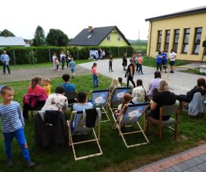 Dorośli siedzą na leżakach, rozmawiają ze sobą