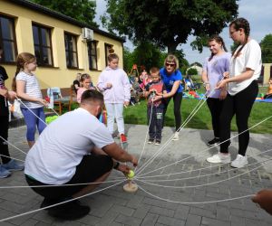 Dzieci stoją w kręgu, w dłoniach trzymają sznurki,