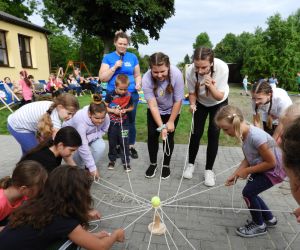 Dzieci stoją w kręgu, w dłoniach trzymają sznurki,