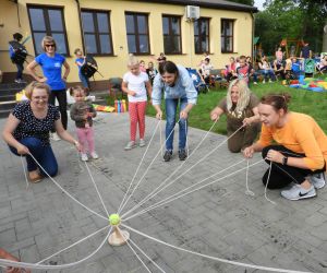 Dorośli stoją w kręgu, w dłoniach trzymają sznurki,