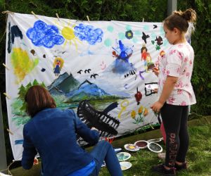 Dziecko stoi przy obrazie pomalowanym przez inne dzieci