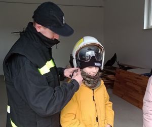 Uczeń przymierza hełm strażacki.