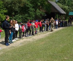 Dzieci stoją jedno przy drugim w szeregu na świeżym powietrzu.