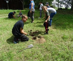Dzieci znajdują się na świeżym powietrzu, kopią w parach dołki, w których będą rozpalały ogień.