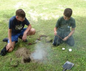 Dzieci znajdują się na świeżym powietrzu, rozpalają ogień.
