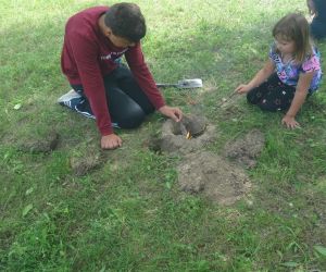 Dzieci znajdują się na świeżym powietrzu, rozpalają ogień.
