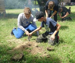 Dzieci znajdują się na świeżym powietrzu, rozpalają ogień.