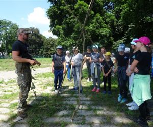 Dzieci znajdują się na świeżym powietrzu, uczą się jak prawidłowo zbudować trójnóg.