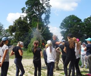 Dzieci znajdują się na świeżym powietrzu, uczą się jak prawidłowo zbudować trójnóg.