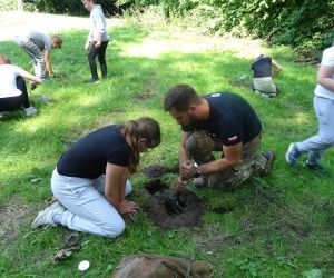 Dzieci znajdują się na polanie i kopią dołki, w których rozpalają ogień.