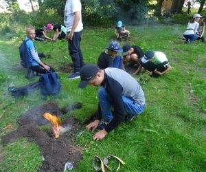 Dzieci znajdują się na polanie i kopią dołki, w których rozpalają ogień.