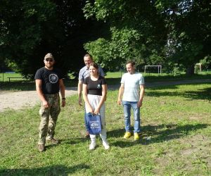 Uczestnik spotkania odbiera nagrodę, która wręcza Wójt Gminy Hrubieszów, radny oraz prowadzący survival.